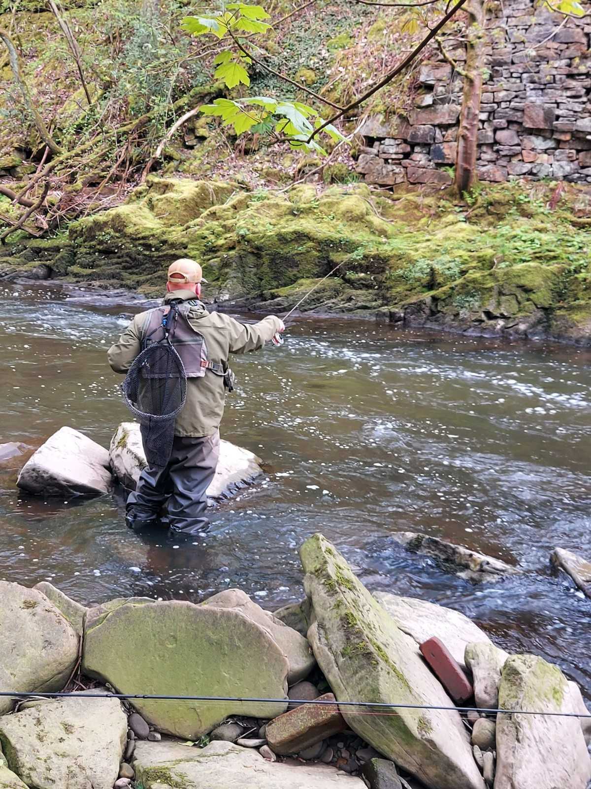 Fisherman casting line in stream